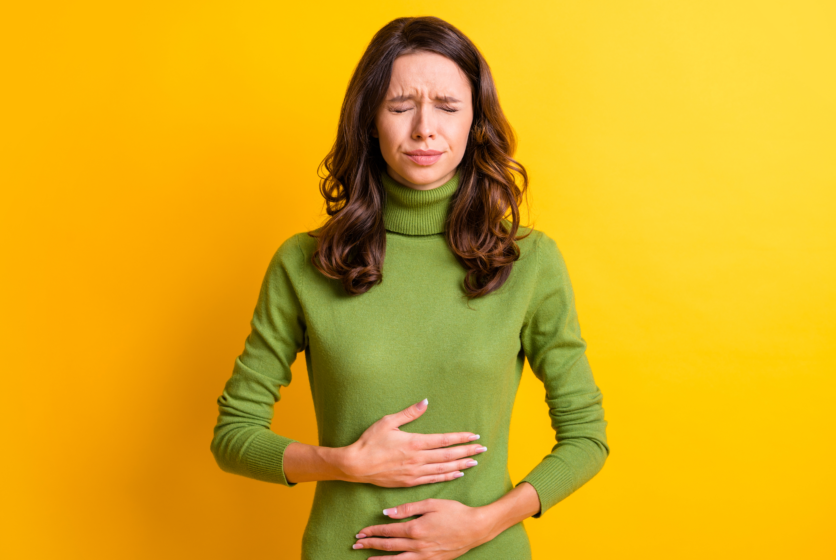 Photo of young unhappy unwell sick ill woman hold hand on stomach suffers pain pms isolated on yellow color background